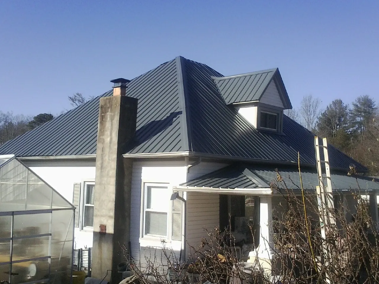 Dark blue standing seam metal roof on a white farmhouse with dormer — Slate & Tile Roof Repair by Roofing Brothers in Pembroke Township