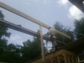 Carpenter setting a ridge beam over a new addition frame — Ice Dam Removal by Roofing Brothers in Pembroke Township