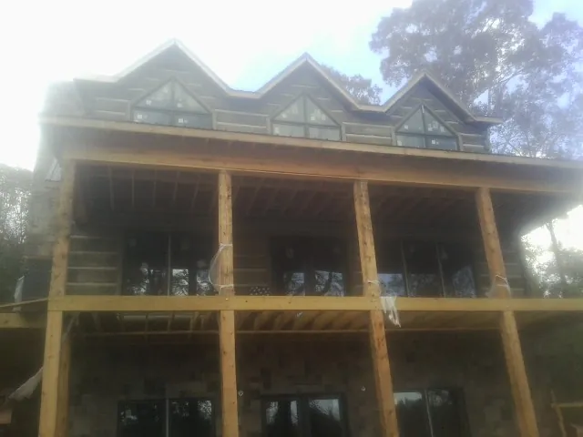 Dormers and porch framing on a large log home under construction — Roof Coating work by our crew in Pembroke Township