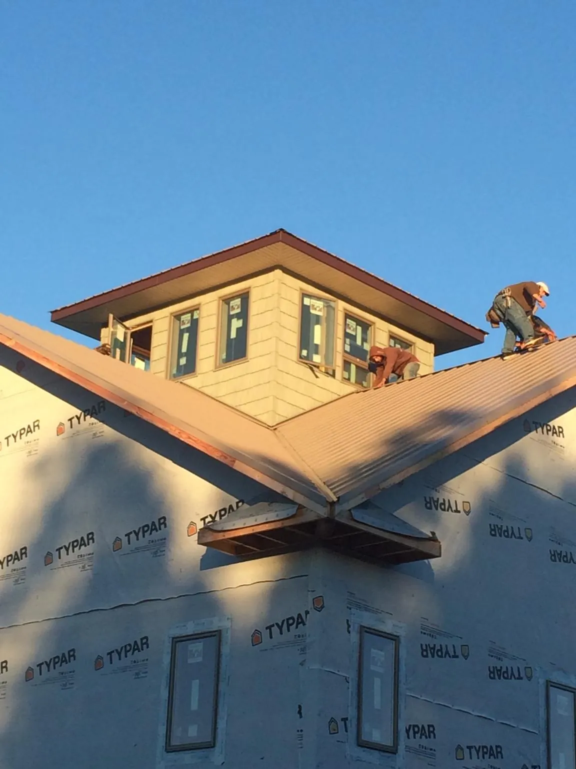 Roofers working around a rooftop cupola on a new metal roof at sunset — Roof Waterproofing in Pembroke Township by Roofing Brothers